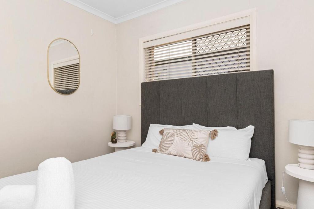 a bedroom with a white bed with a large headboard at Wagga CBD Apartments in Wagga Wagga