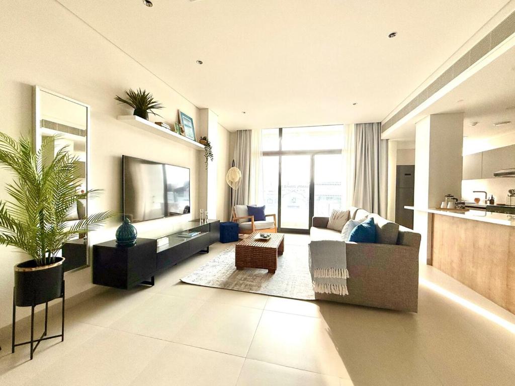 a living room with a couch and a tv at By The Beach - Prime location in Sarūq