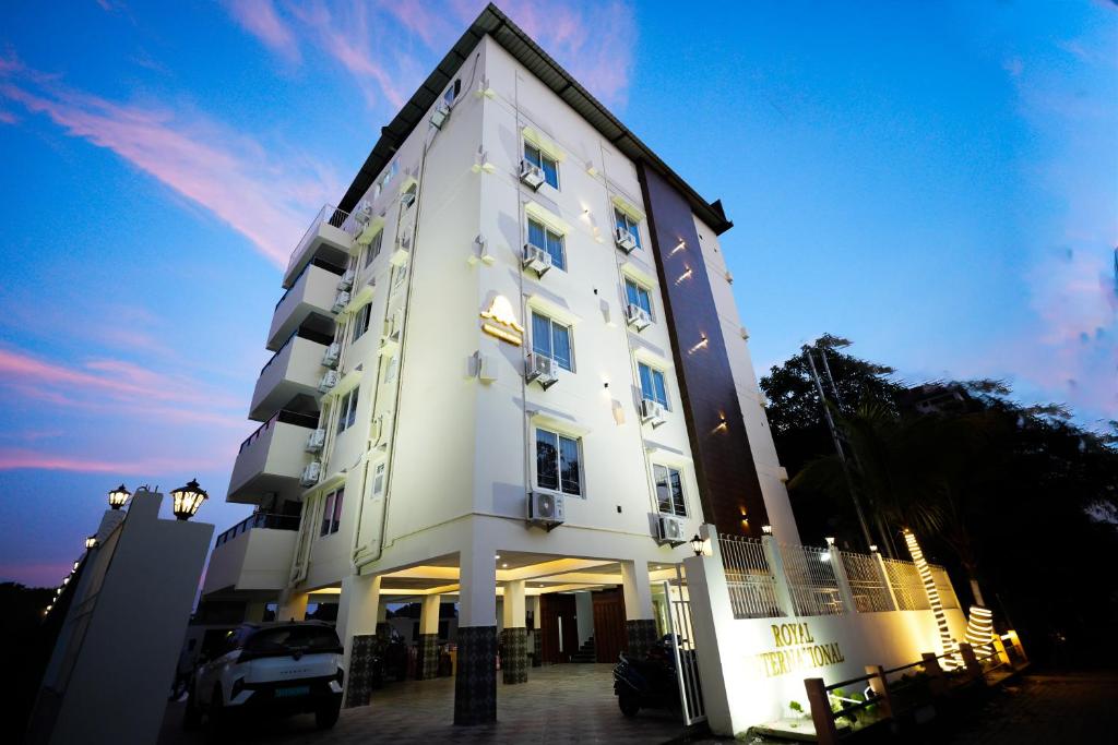 Un edificio blanco con un coche aparcado delante. en Hotel Royal International - Best Boutique Hotel Near Airport & Kamakhya Temple, en Guwahati