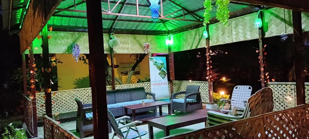 un patio con banco, mesas y sillas en Bongheri Homestay, 