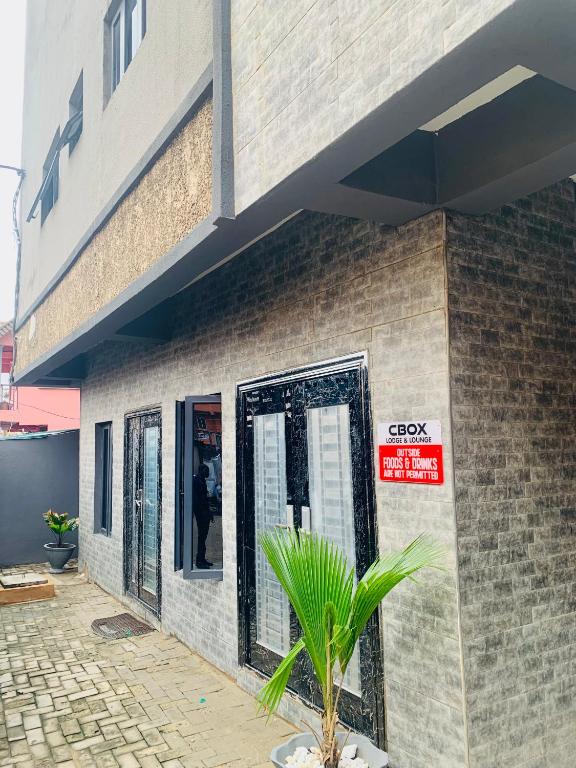 a building with a palm plant in front of it at Cbox Lodge & Lounge in Lagos