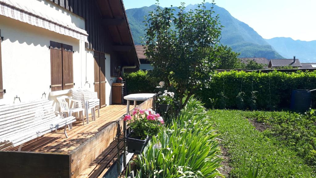 une véranda avec un banc, une table et des fleurs dans l'établissement Chalet coocooning, à Marlens