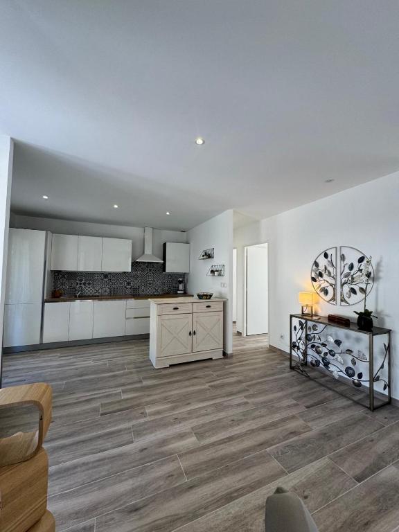 a large kitchen with white walls and wooden floors at Villa Maeva Florensac in Florensac