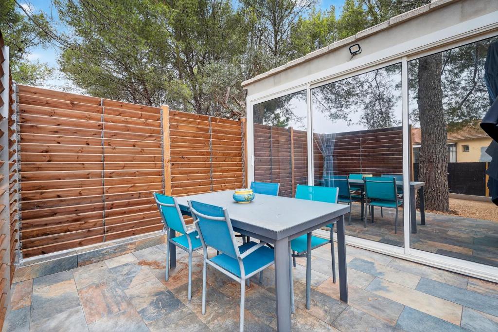 Un patio con mesa y sillas y una valla. en Cabanon des Amandiers, en Sanary-sur-Mer