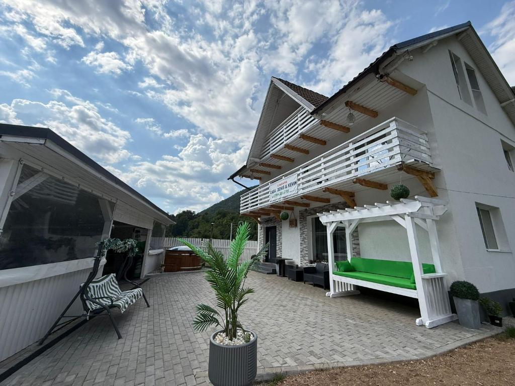 a white house with a porch and a bench on a patio at Casa Denis & Kevin in Petrila
