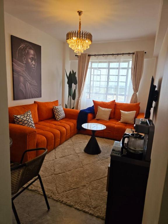 a living room with an orange couch and a table at Rustic Paradise Apartments in Kisumu
