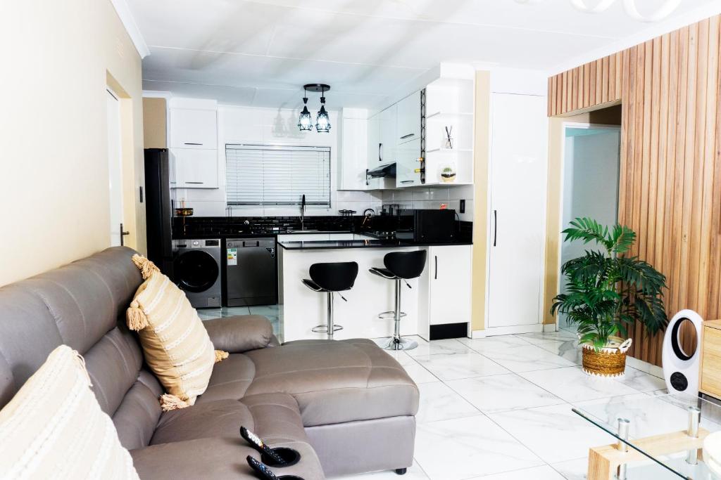 Una sala de estar con un sofá y una cocina. en ADAIA GUEST Apartments, en Johannesburgo