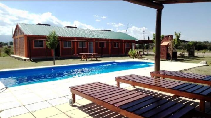 una piscina con 2 bancos frente a un edificio en Nuevo Aire, en Santa Rosa del Conlara