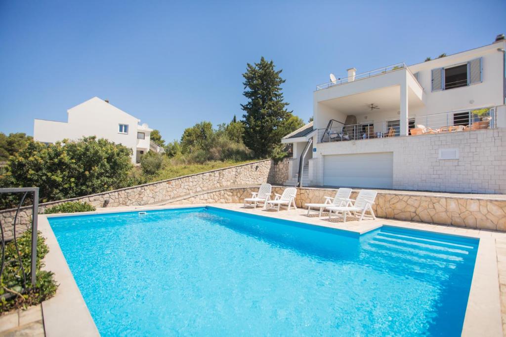 a swimming pool with two chairs and a house at Amazing Mediterranean view Villa Oliva Zaboric in Zaboric