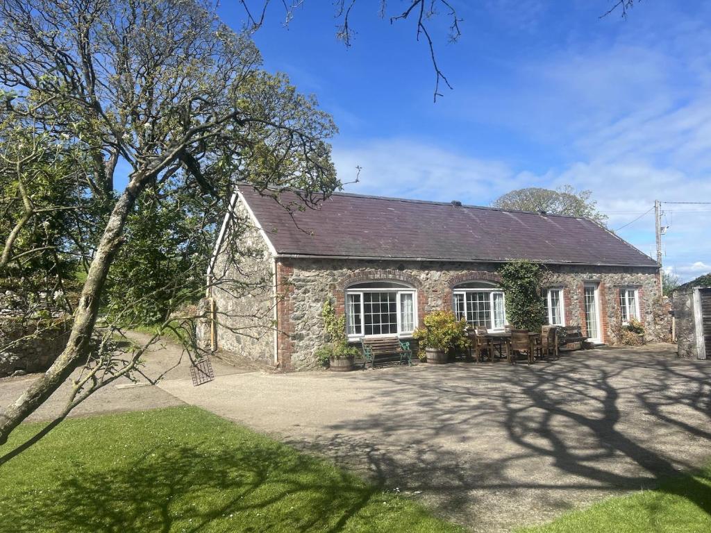 an old stone house with a patio in front of it at Y Berllan in Caernarfon