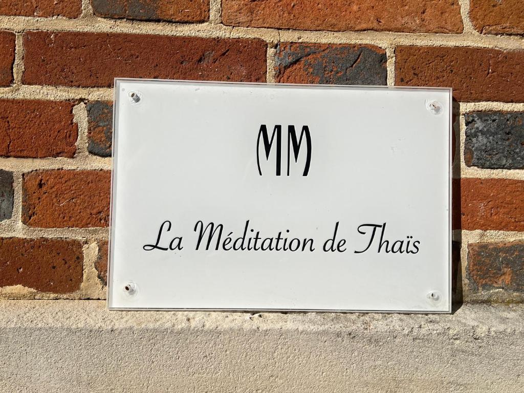 a sign on the side of a brick wall at La Méditation de Thaïs in Vertus