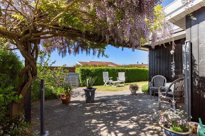 a patio with a tree with purple flowers on it at Summer Cottage Idyll In Charming Karrebæksminde! in Karrebæksminde