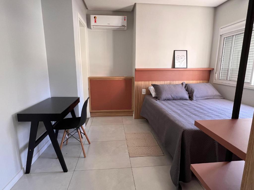 a small bedroom with a bed and a desk at Charmoso apê, perto da faculdade e da gastronomia in Passo Fundo