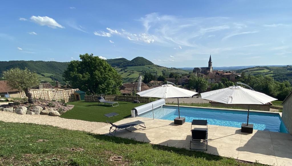 a swimming pool with two umbrellas at Les Raspes du Samphy in Saint-Victor-et-Melvieu