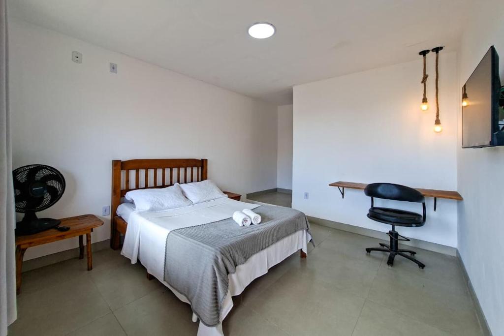 a bedroom with a bed and a desk and a chair at Suíte casal in Arraial do Cabo