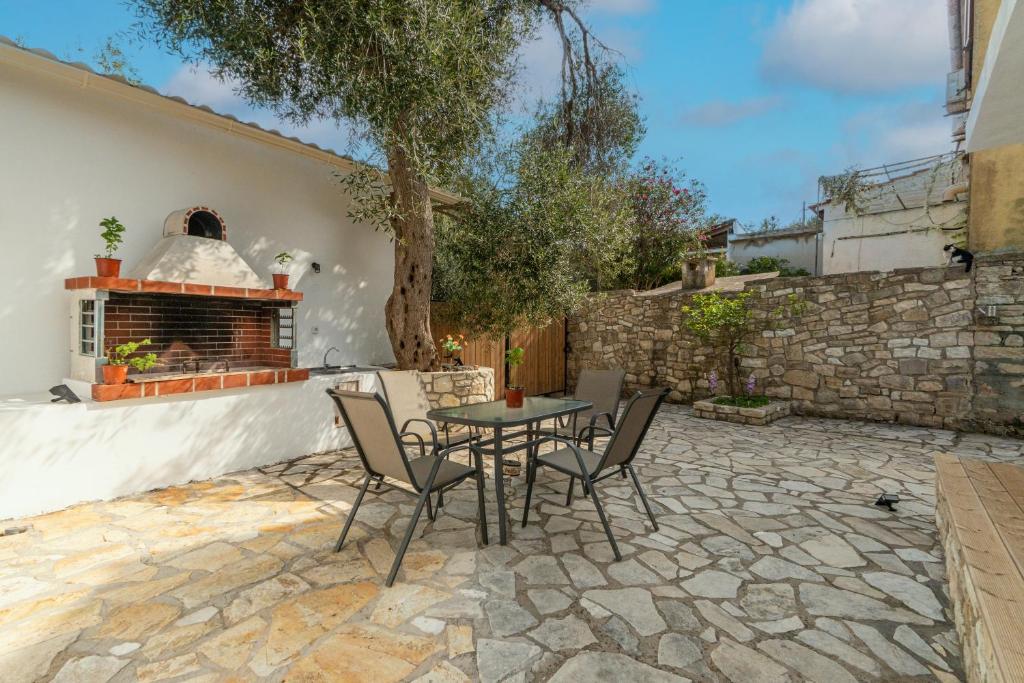 Un patio con mesa y sillas y una chimenea. en Serenity Paxos, en Gáios