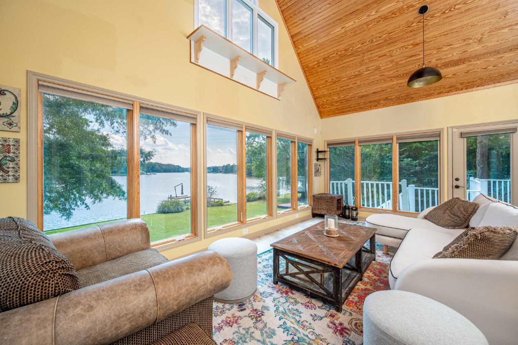 a living room with couches and a table and windows at Lake Days Getaway in Hillsborough