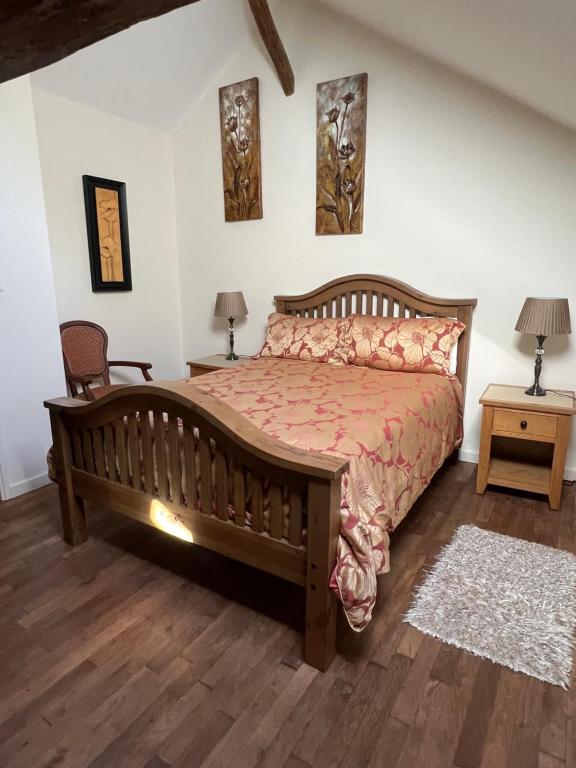 a bedroom with a large wooden bed and two lamps at Wisteria cottage in Bersac-sur-Rivalier