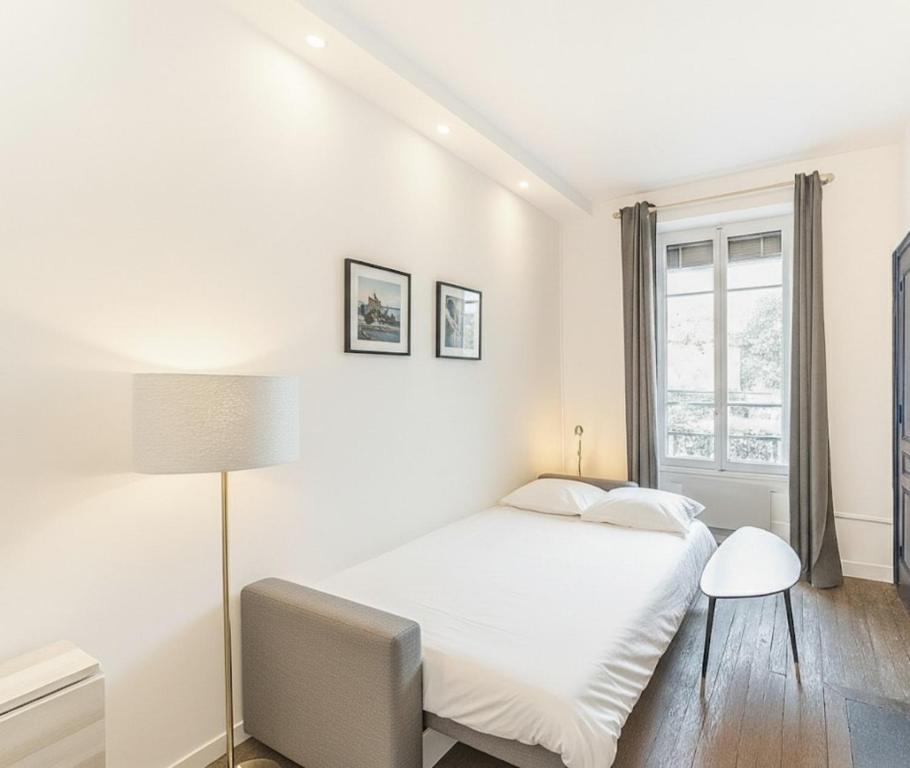 a white bedroom with a bed and a window at Le Nid de Perrache Comfortable and Stylish Studio in Lyon