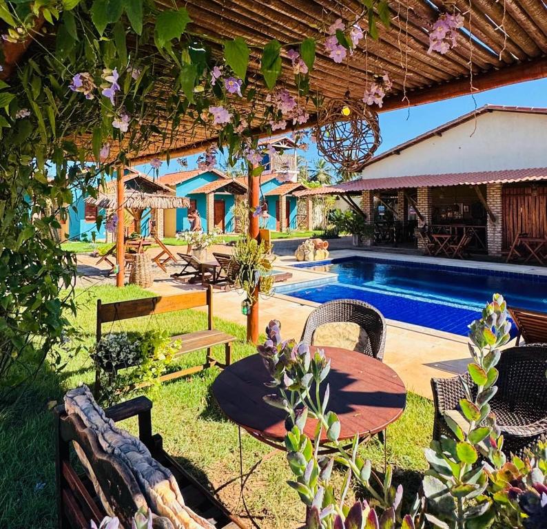 a patio with a table and chairs next to a pool at POUSADA DONNA MARIA in São Miguel do Gostoso