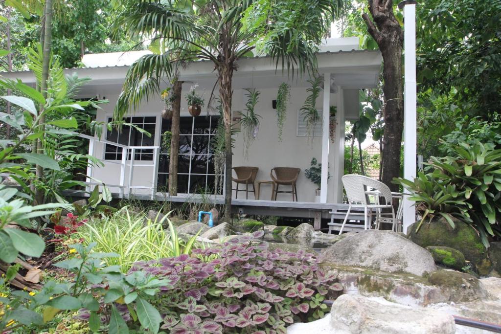 una casa bianca con due sedie in un giardino di Homeku Guesthouse Room 4 Cozy Stay Close to Suvarnabhumi Airport a Lat Krabang