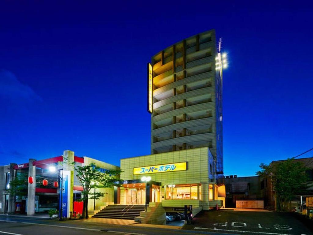 a tall building on a city street at night at Super Hotel Minamata in Minamata