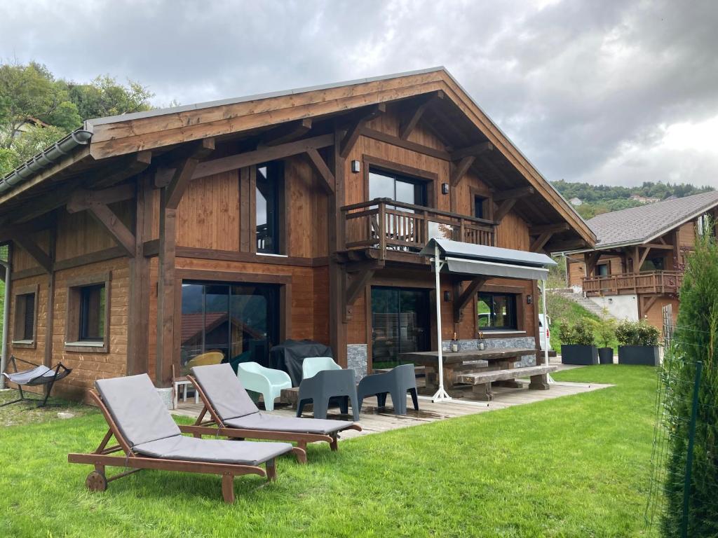 a log house with chairs and a deck with a grill at Le Chalet Margaux La Bresse in La Bresse