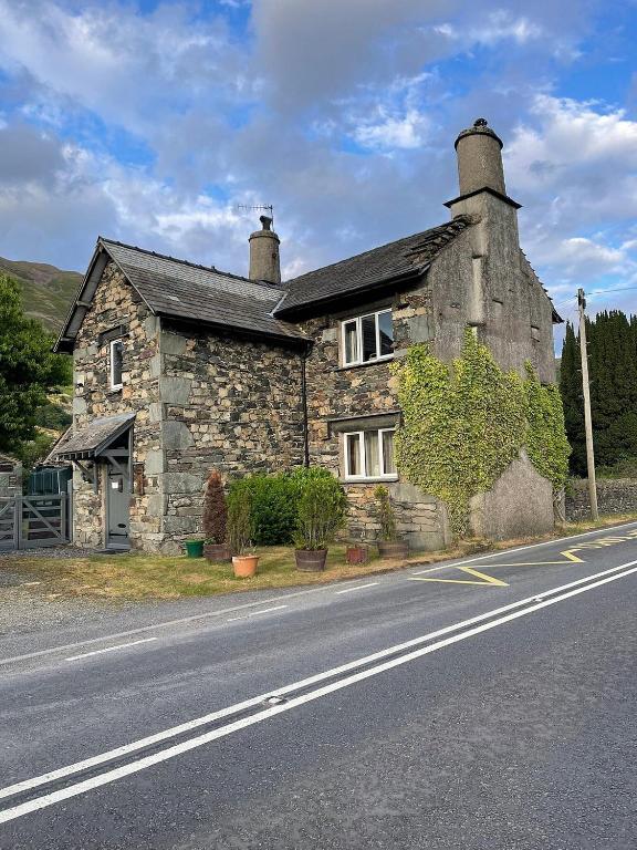an old stone house on the side of a road at School House in Patterdale