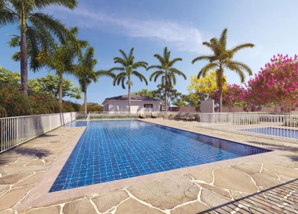 a swimming pool with palm trees in the background at Apartamento novo, mobiliado e com ótima localização in Barretos