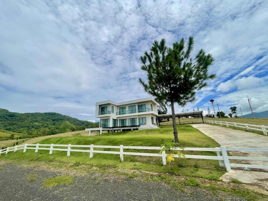 a house on a hill with a white fence and a tree at Cloud N Wind Khao Kho Thailand in Ban Lao Kok Kho