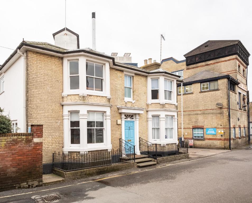 a brick house with a blue door on a street at The Brewer's House in Southwold