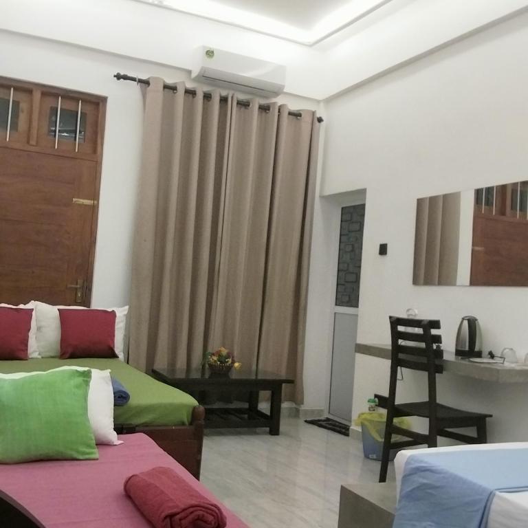 a room with two beds and a window with curtains at Rooms in galle in Galle