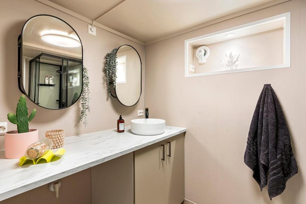 un baño con lavabo y dos espejos en Modern basement apartment, en Stavanger