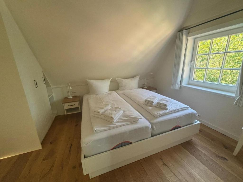 a white bed in a room with a window at Nebel-s-Hues-Og in Nebel