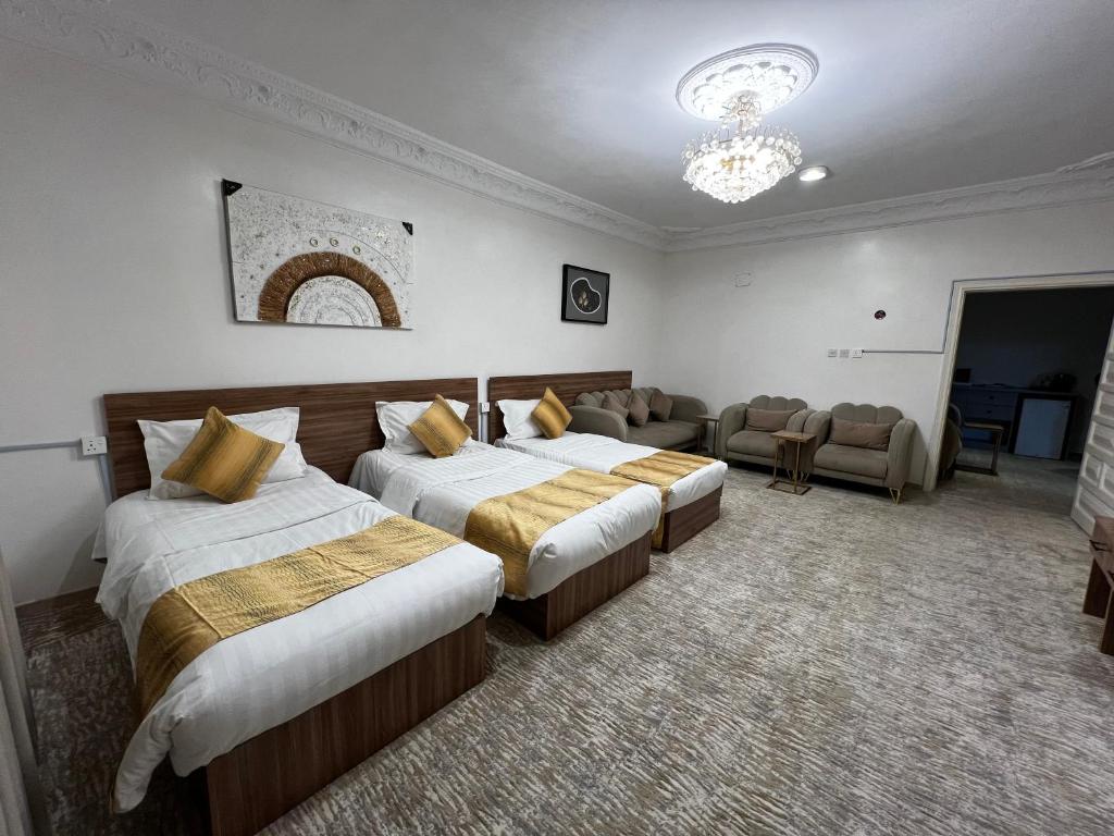 a hotel room with two beds and a couch at شقة خاصة من غرفتين قريبة من المسجد النبوي in Al Madinah