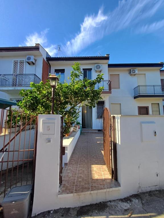 a white house with a gate and a brick sidewalk at La Villetta di Odisseo in Terracina