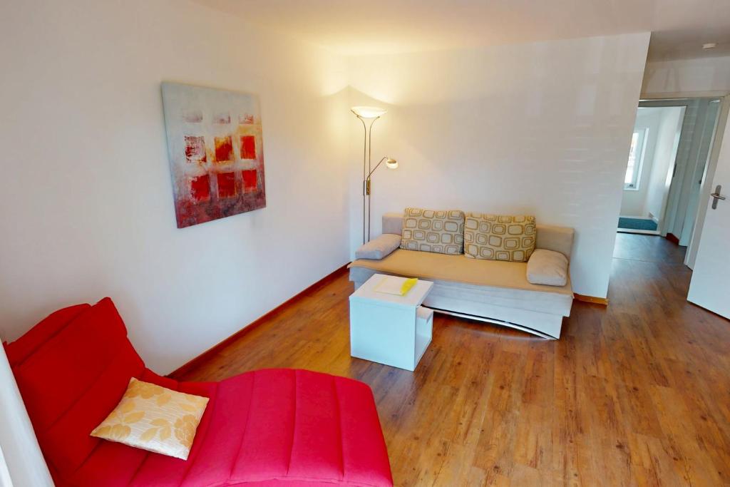 a living room with a couch and a red chair at Kurpark Suites Bad Aibling in Bad Aibling