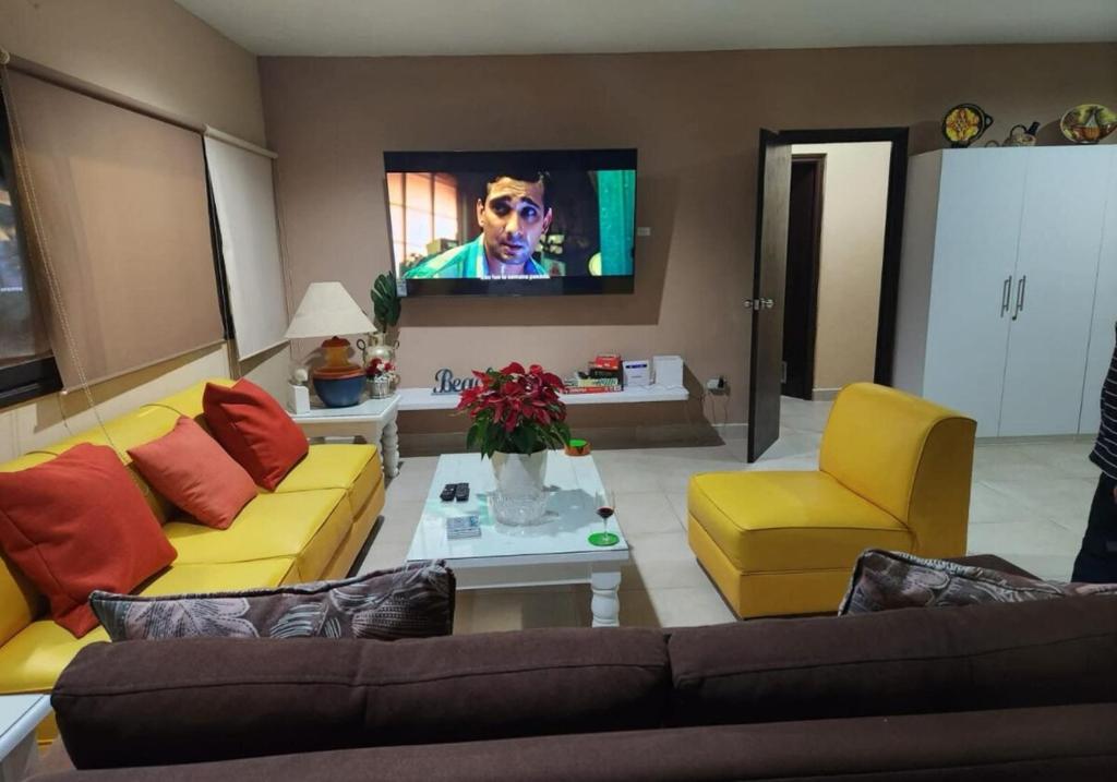 Una sala de estar con un sofá y un televisor. en Essenz Bahía, en El Níspero