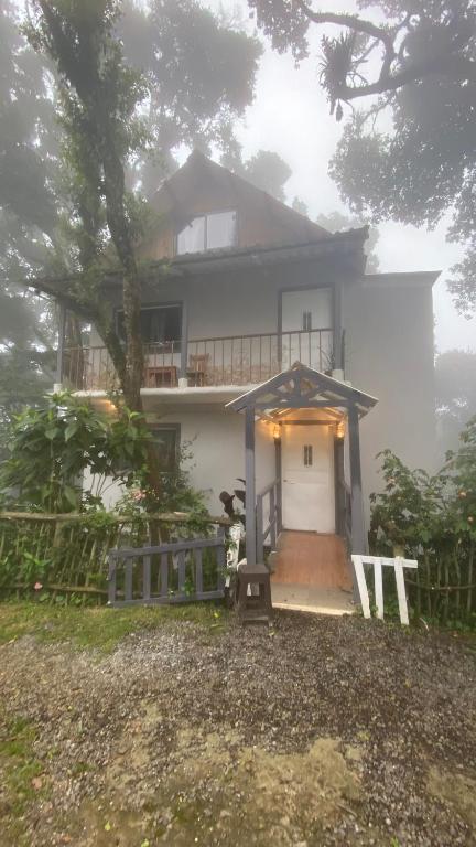 a white house with a porch and a fence at La Casona entre el Bosque in Guatemala
