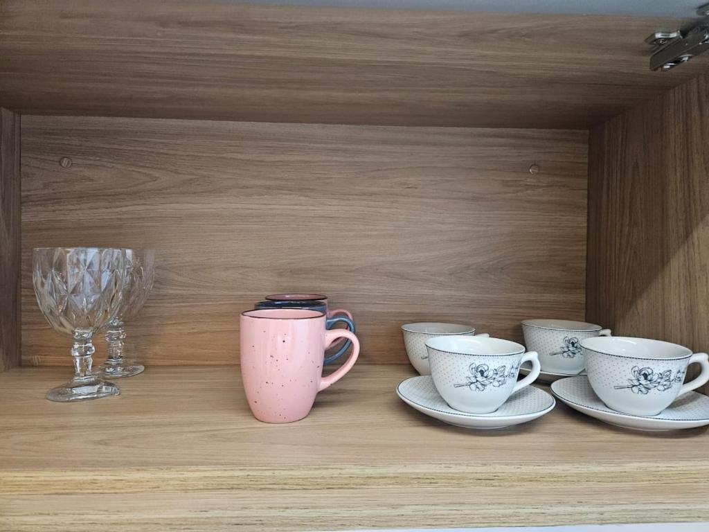 a shelf with cups and plates and a wine glass at Travellar Apt 91 - Admirável - Monte Carmelo in Ribeirão Preto