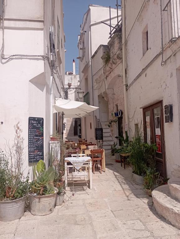 an alley with an umbrella and tables and chairs at Casa Checco in Cisternino