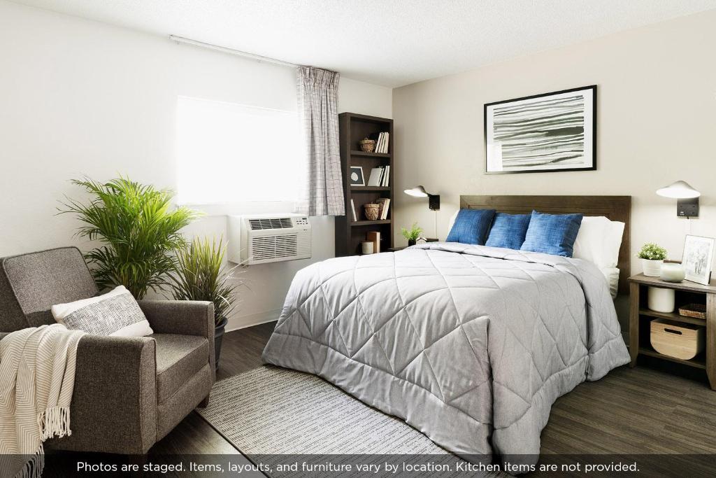 a bedroom with a bed and a chair and a window at InTown Suites Extended Stay Matthews NC - East Independence in Charlotte