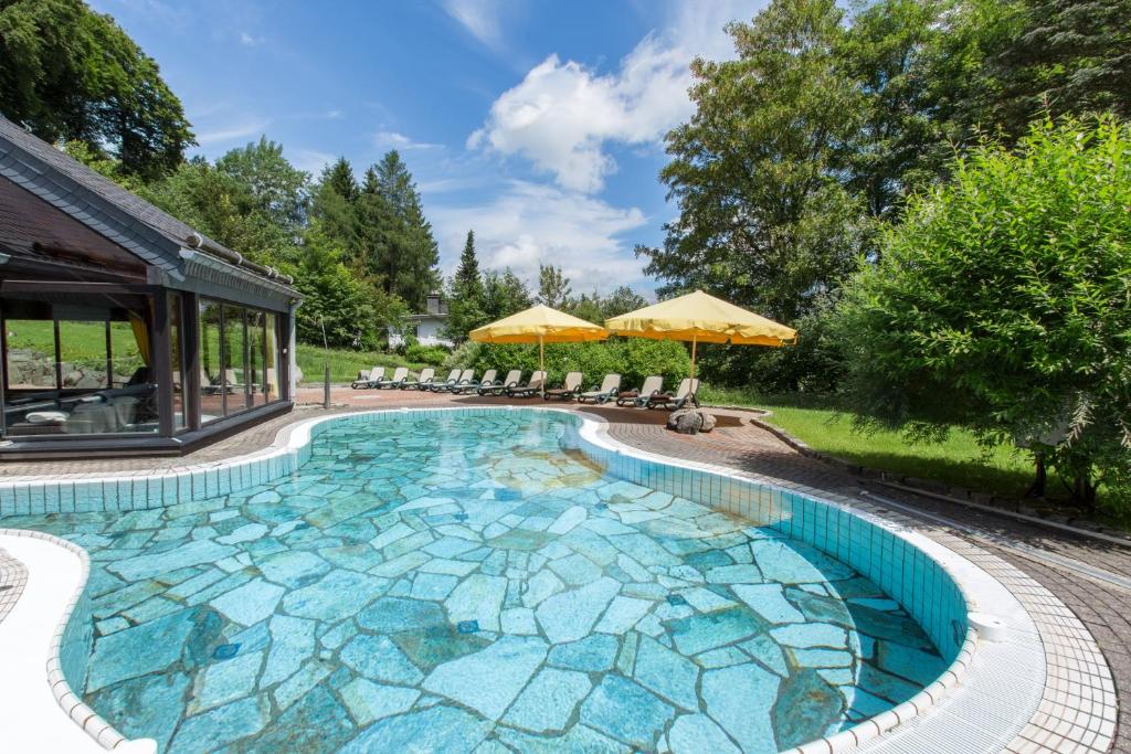 een groot zwembad met blauwe mozaïeken in een tuin bij Romantik Hotel Stryckhaus in Willingen