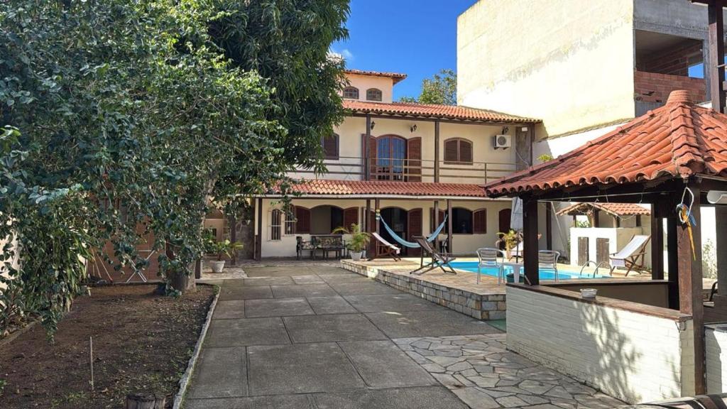 a house with a swimming pool and a gazebo at Villa Palmeiras Suítes in Cabo Frio