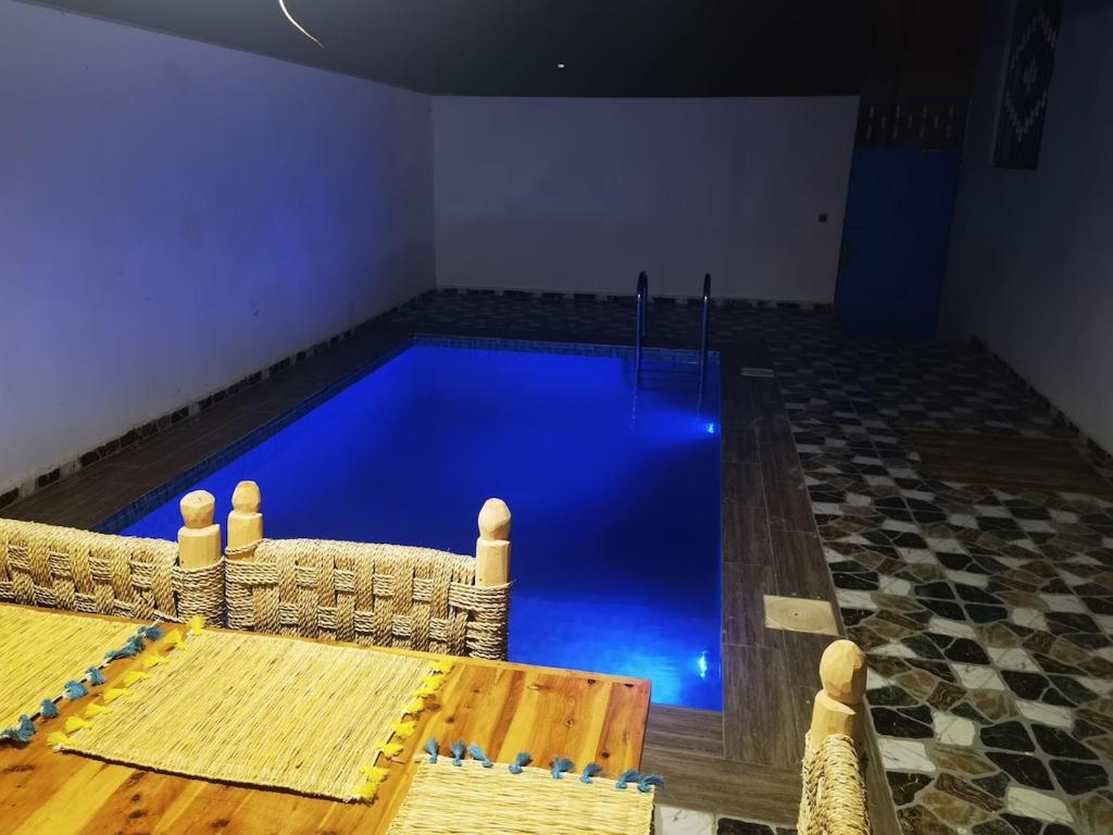 a swimming pool with blue water in a room at Reda House in Ikouzza