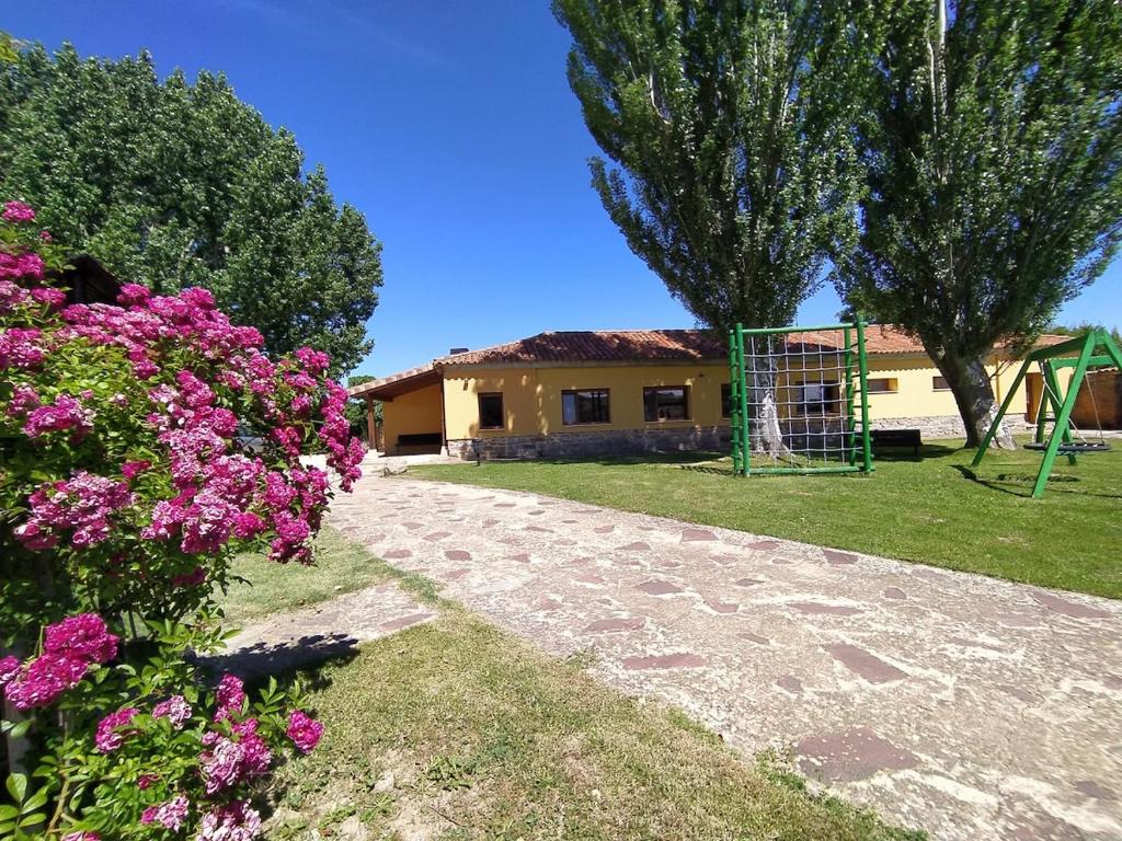 a house with a playground in a yard with flowers at Alojamiento Rural La Arboleda in Noviercas