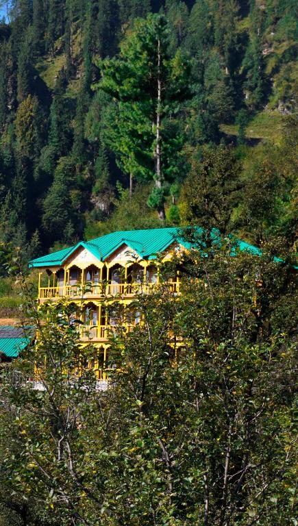 a large yellow building with a blue roof at Himalayan Homestay Gadagusain in Jibhi