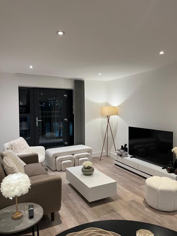a living room with white furniture and a large television at Birmingham City Center View in Birmingham
