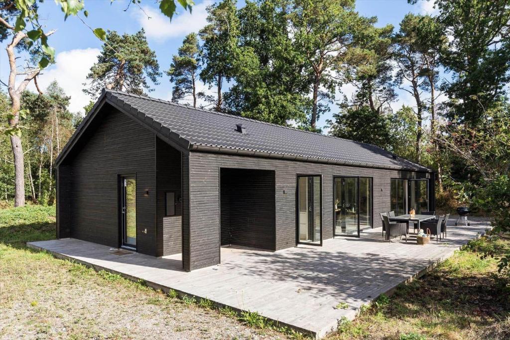 a small black building with a patio in a field at 8243-Knebel-Metholmvej-18 in Knebel