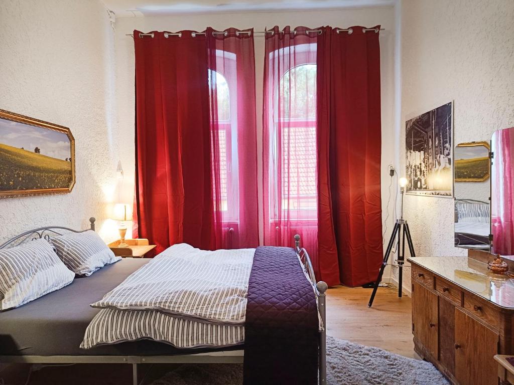 a bedroom with red curtains and a bed and a desk at petite chambre in Halle an der Saale